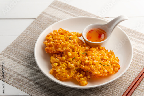 Deep Fried Corn Cake,Crispy Corn Fritters in white plate.with chilli sauce.