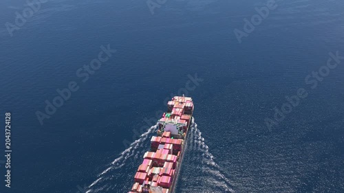 Aerial top-down view of a fully loaded cargo container ship sailing across the vast open blue ocean, illustrating global trade, logistics, and international maritime shipping industry