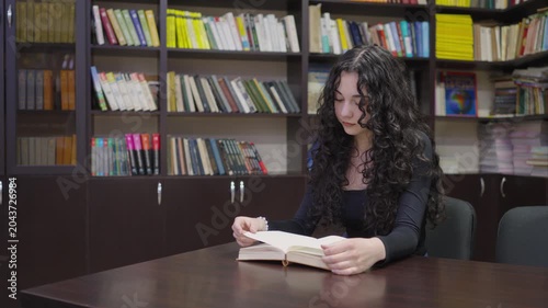 Teenage student girl working with a book in the school library