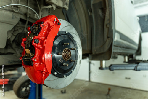 Bild auf Leinwand Close view of a bright red brake caliper mounted on a ventilated brake disc and