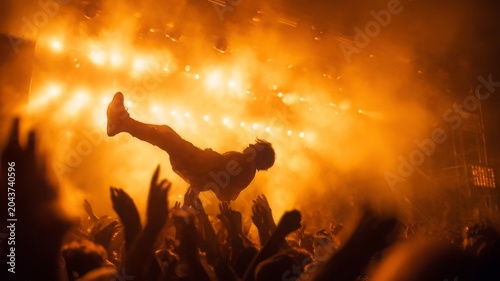 An audience enjoys a rock concert with a fan crowd surfing in the foreground. 