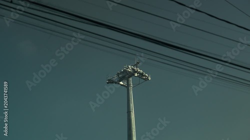 Cell phone tower antenna behind tangled power lines in Latin American urban area