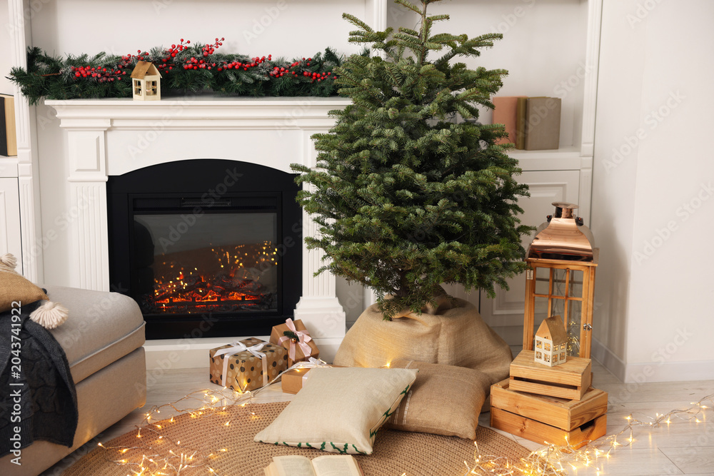 Fototapeta premium Beautiful Christmas tree and other festive decor near fireplace in living room