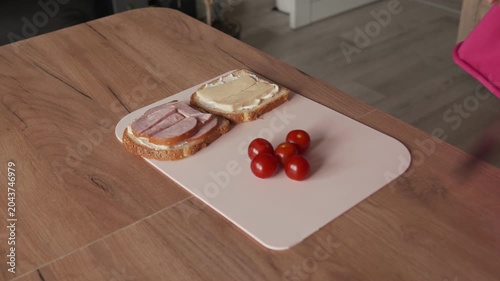 The housewife takes out cherry tomatoes in order to add them to the sandwich filling.