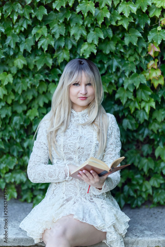 Adult woman seated outdoors in white dress