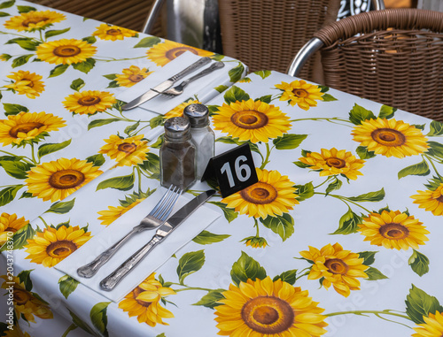 Knife and fork on a napkin, along with salt, pepper, and a table number, on a sunflower design table cloth