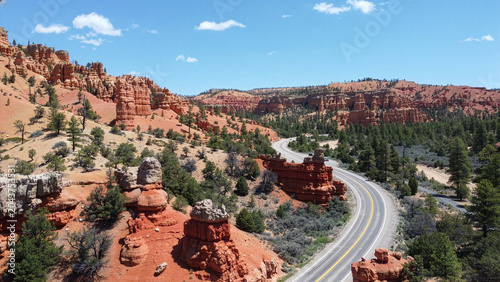 Foto Breathtaking drone shot of a winding asphalt road with cars driving through lush green valleys in Dixie National Forest