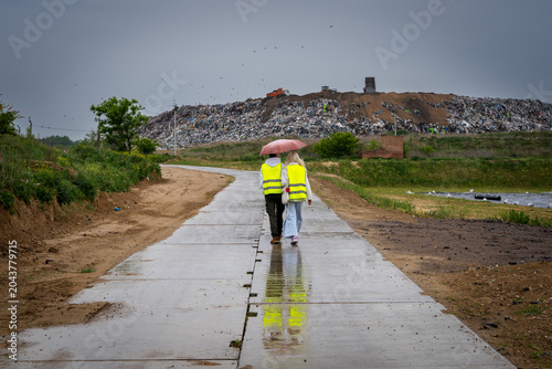 A young couple is walking past a landfill near the city