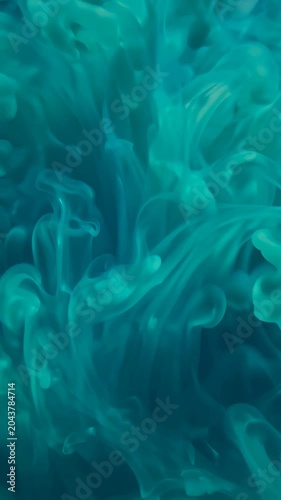A vibrant, swirling mass of turquoise-colored smoke or ink suspended in a dark blue liquid, creating an ethereal and mesmerizing visual effect