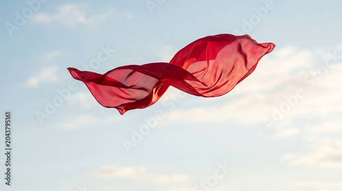 Minimalist view of red fabric floating in the sky