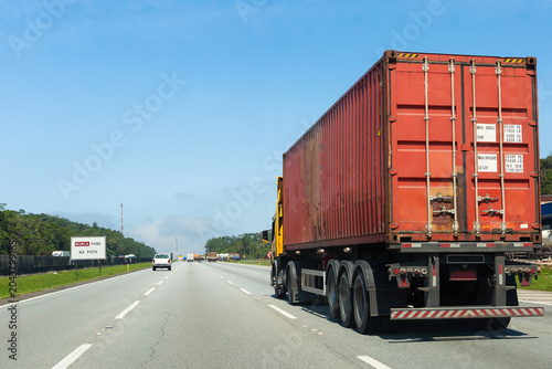 Cargo container truck driving on a highway during a sunny day.