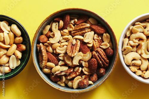 Photos Mixed nuts in bowls on yellow background