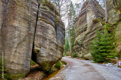 Bild auf Leinwand Narrow pathway through majestic rock formations in winter forest