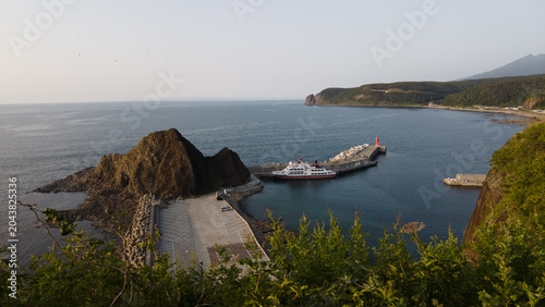 Foto Coastal harbor with passenger ferry and breakwater at sunset