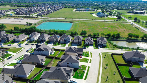 Foto Turquoise pond outlook in Arlington, Texas highlights rows of homes arranged along grid pattern with open fields two water bodies extending behind them