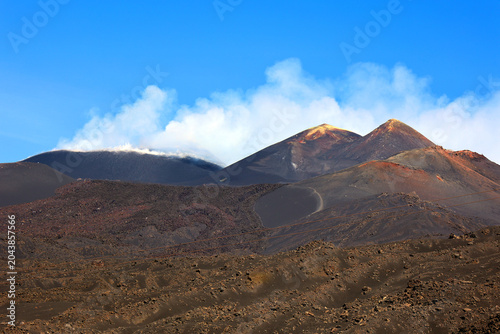 The Etna volcano crater. Black Volcanic Earth, Volcanic Lava and Stones. Smoke on Mount Etna The island of Sicily, Italy.