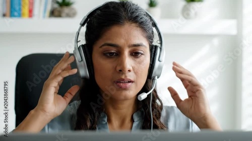 Professional woman wearing a headset while working on a computer in a home office