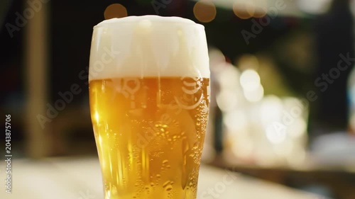Refreshing Golden Beer with Frothy Head, Bubbles Rising, Soft Bokeh Lights Background.