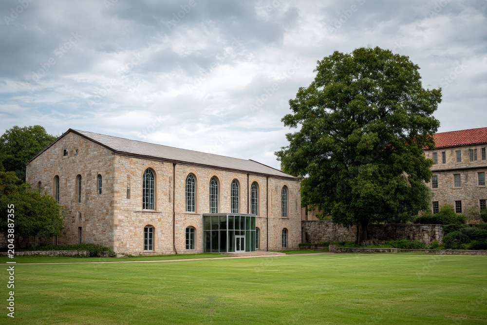 Fototapeta premium Historic Stone Building with Large Green Lawn and Mature Tree.