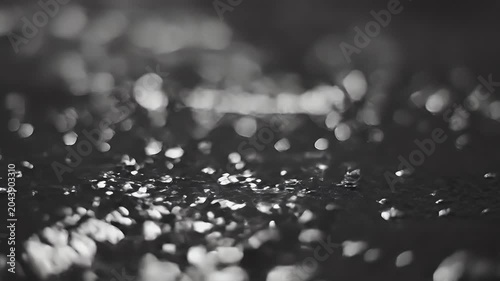 Macro close-up of glistening water droplets on a dark wet shoreline surface at dusk
