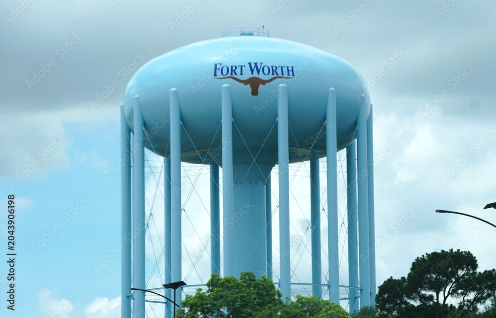 Naklejka premium Northern Texas, U.S - May 27, 2026 - Light blue Fort Worth water tower with longhorn emblem supported by multiple columns under partly cloudy sky.