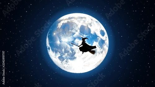 Silhouette of a witch riding a broomstick flying across a giant glowing full moon in the starry night sky