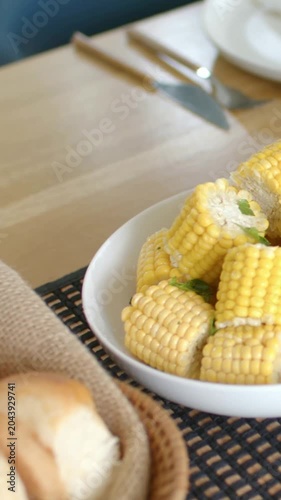 Vertical video: Panning cam right, corn bowl moving across table, revealing bread basket and fork