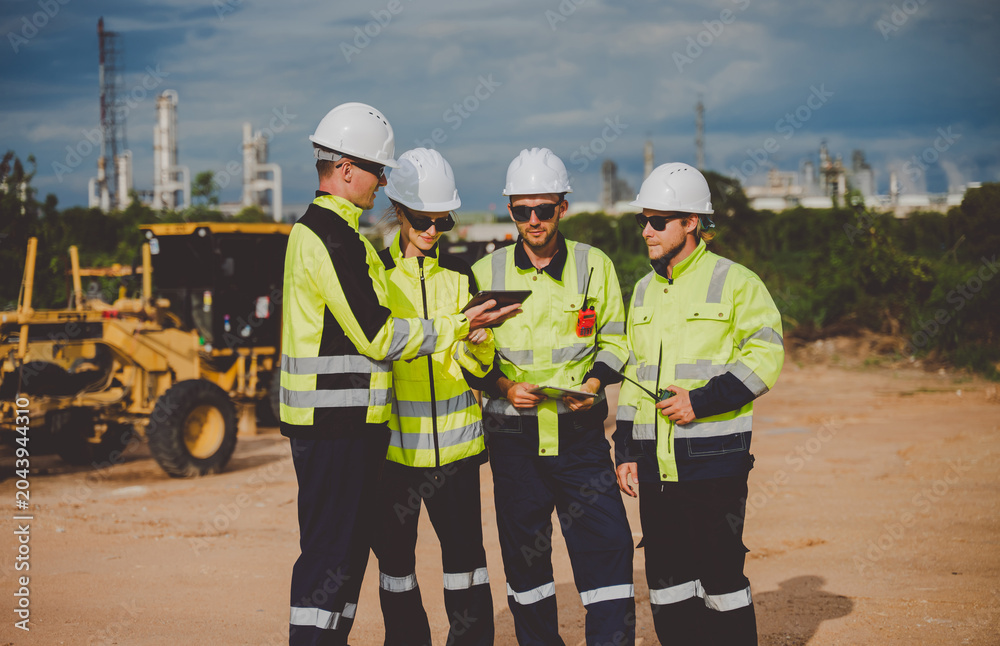 Fototapeta premium Engineers reviewing plans on tablet at oil and gas refinery site for inspection and management