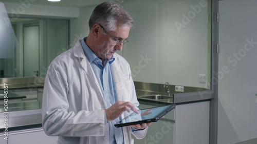 Senior Scientist Analyzing Data on Tablet in Modern Laboratory