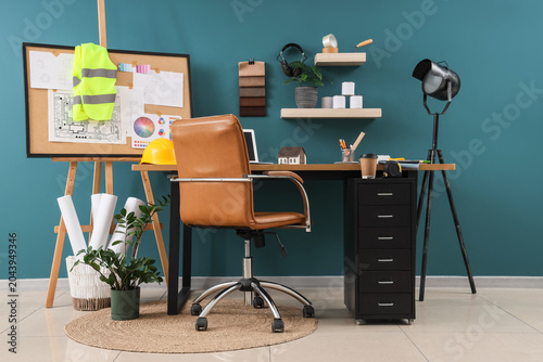 Interior of modern architect's workplace with safety vest, cork board, bluepr...