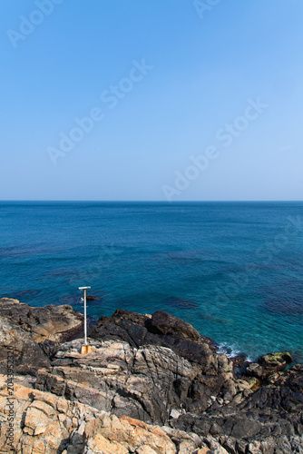 Small white pole structure on a rugged coastal cliff overlooking the sea