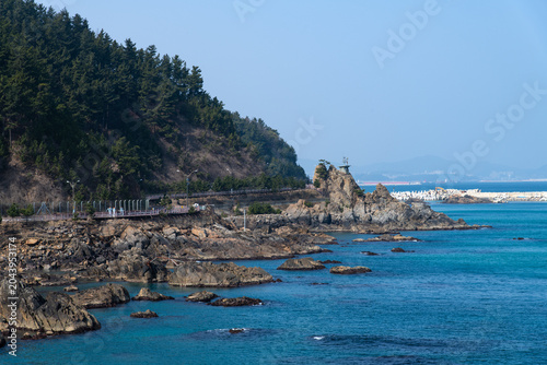 Coastal boardwalk trail along a green mountain and rocky shore
