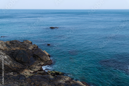Rugged dark rocky coast meeting the vast blue ocean horizon