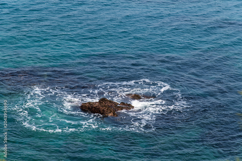 Fototapeta premium Ocean waves crashing against a rocky reef in turquoise sea