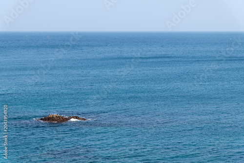 Small rocky reef in the middle of vast blue ocean
