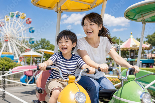 遊園地のサイクリング型乗り物を楽しむ日本人の母と息子　夏休み