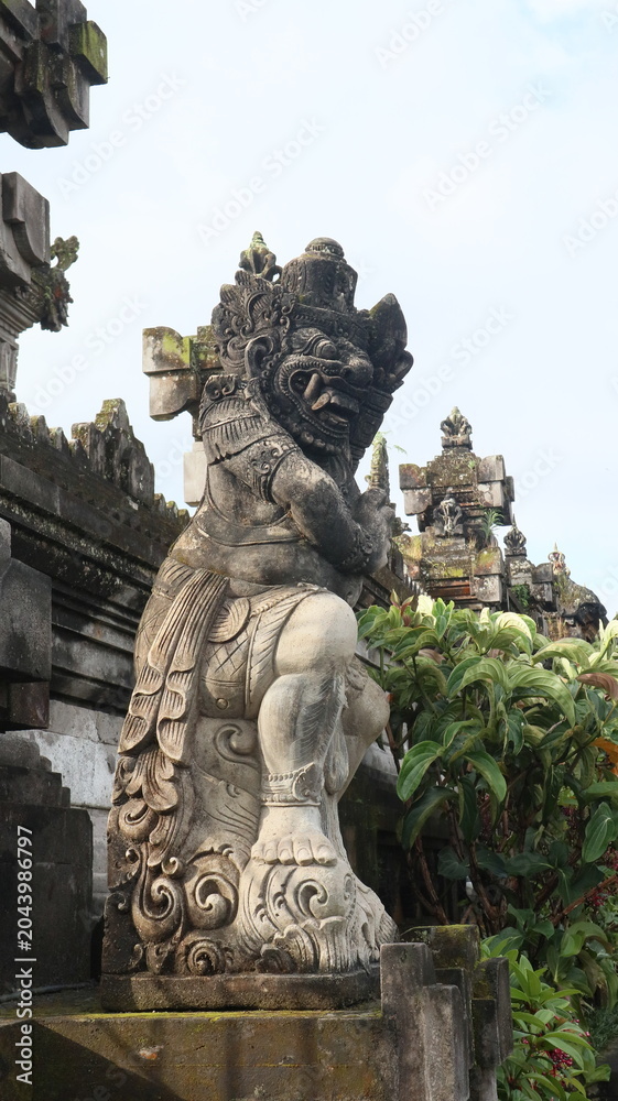 Fototapeta premium Giant statues, also known as bhuta kala, Dwarapala, gatekeeper statues carrying cups, torches, and weapons, with frightening faces. They wear Balinese poleng cloth. Photo raw, no edit.