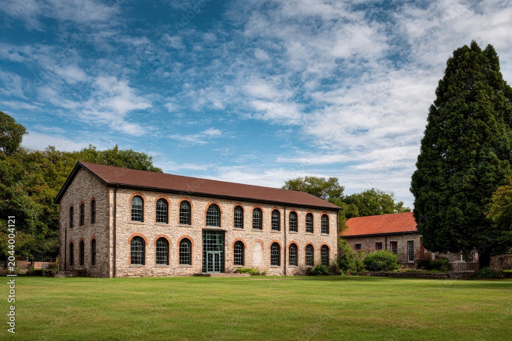 Fototapeta premium Historic Stone Building with Arched Windows and Large Green Lawn.
