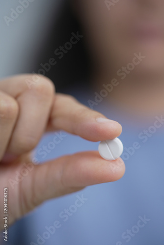woman is holding headache pills to reduce her fever.	
