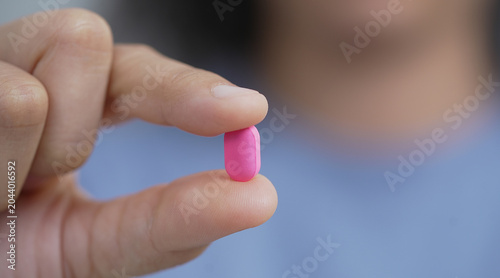 woman is holding headache pills to reduce her fever