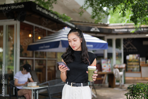 Young woman checking phone enjoying drink outdoors cafe