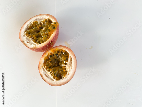 Fotografie Two halves of a ripe passion fruit on a white surface