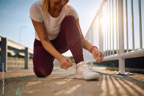 Obraz na plátně Close up of runner tying her shoelaces during outdoor workout.