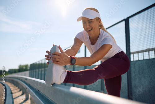 Konstfotografi Happy sportswoman doing stretching exercises while working out outdoors