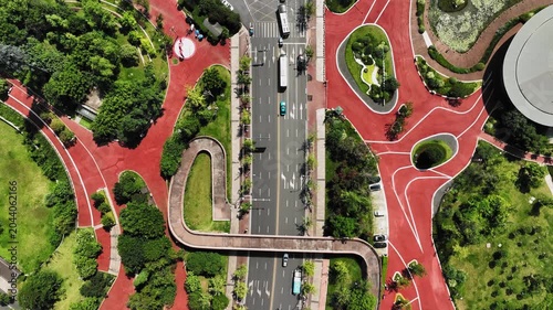 Aerial View of Curved Pedestrian Bridge Over City Road in Urban Park