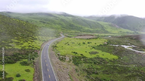 Aerial View of Winding Mountain Road Through Misty Green Valley