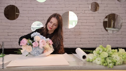 Florist wrapping bouquet on worktable in flower shop