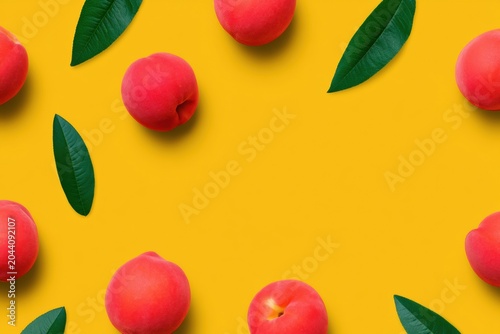 Yellow background with ripe red peaches and green leaves scattered around empty copy space for fruit branding, seasonal food styling and summer grocery advertising
