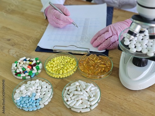 Scientist examines pills and capsules while taking notes