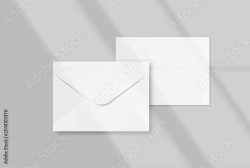 Envelope and blank invitation card mockup on background with soft natural window shadows. Template for wedding stationery printing, greeting cards, and corporate identity design.
